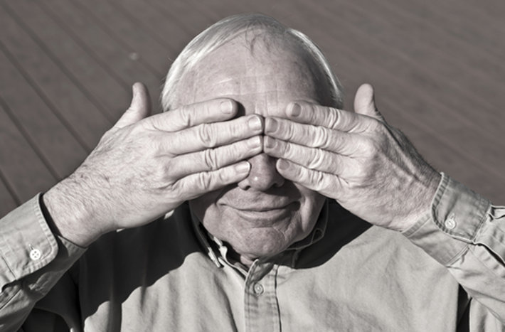 Anziano che si copre gli occhi